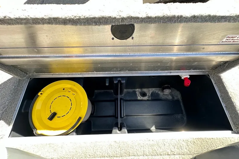 Slide: The Image of Open storage compartment in 2012 Tracker Pro Team 175 TXW boat, featuring a yellow container. - 26