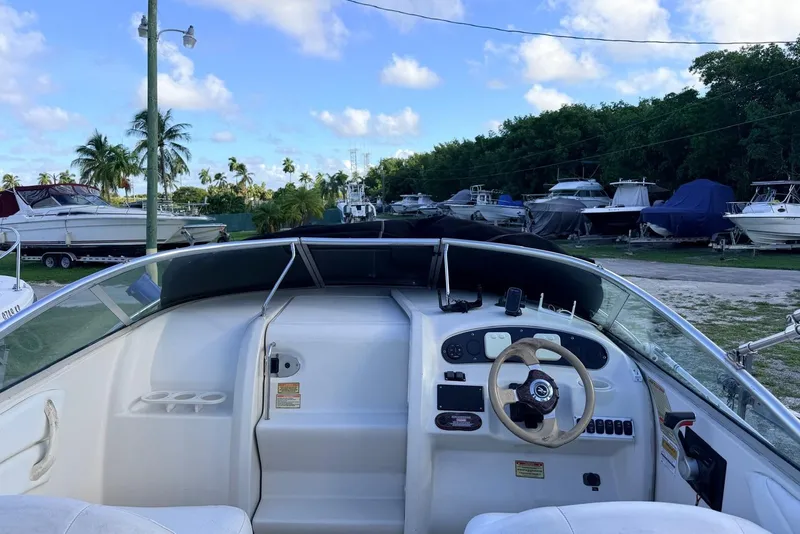 Slide: The Image of 2002 Sea Ray 225 Weekender boat interior with steering wheel, docked among other boats. - 8