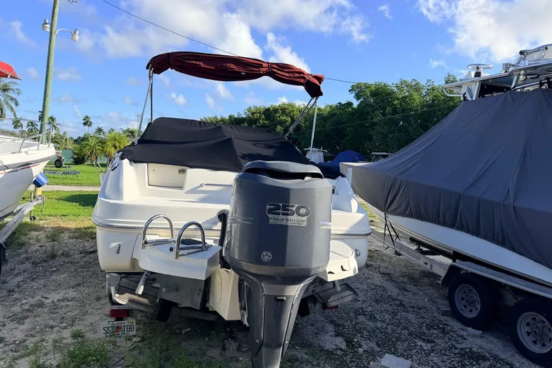 Slide: The Image of 2002 Sea Ray 225 Weekender boat with outboard motor, parked outdoors under blue sky. - 1