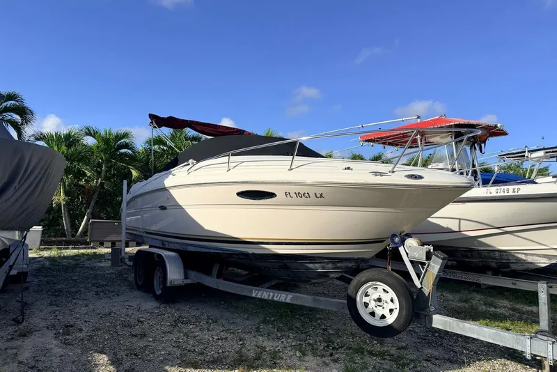 The Image of 2002 Sea Ray 225 Weekender boat on trailer, parked outdoors under clear blue sky. - 0