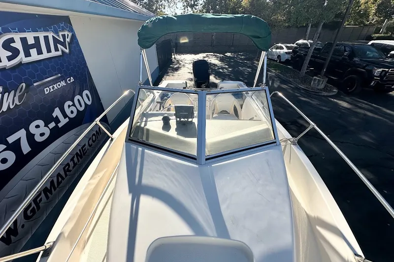 Slide: The Image of 2005 Trophy 1802 Walkaround boat with green canopy, docked near a marine service center. - 7