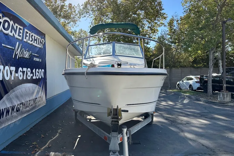 The Image of 2005 Trophy 1802 Walkaround boat on trailer at dealership, surrounded by trees. - 0