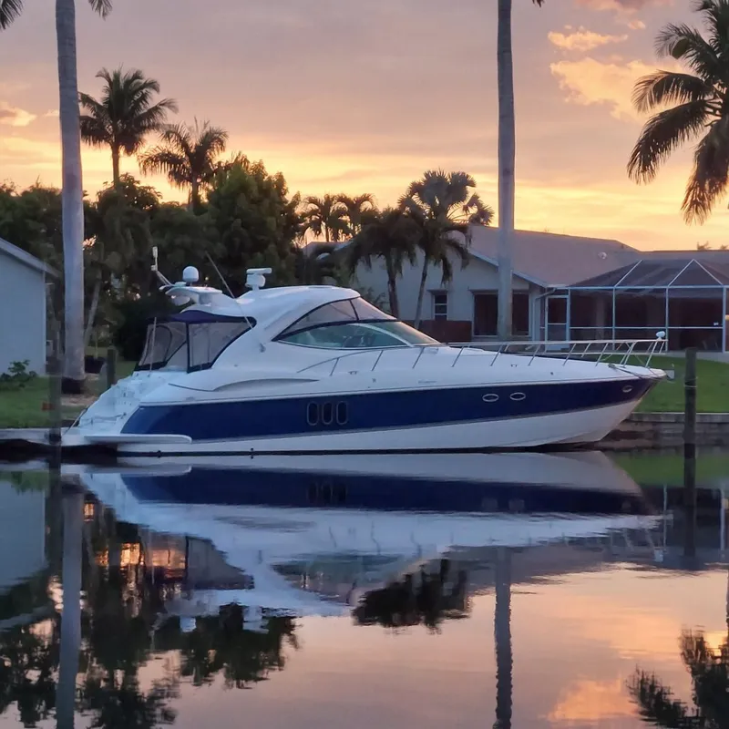 The Image of 2006 Cruisers Yachts 520 Express docked at sunset, surrounded by palm trees. - 0
