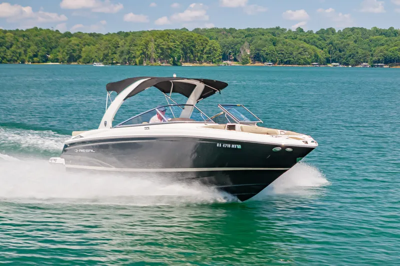 The Image of 2015 Regal 2700 ES Bowrider cruising on a scenic lake with lush green shoreline. - 0
