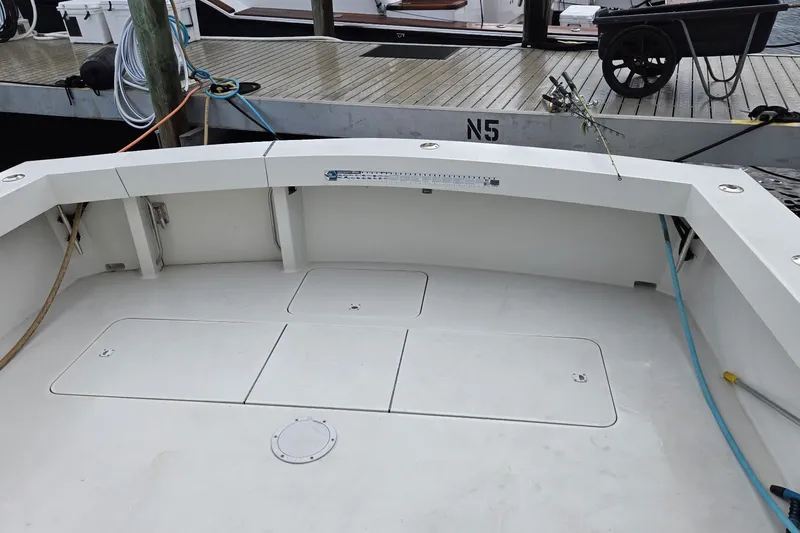 Slide: The Image of 1989 Viking 45 Convertible boat deck at dock, featuring clean white surface and fishing rod holders. - 5