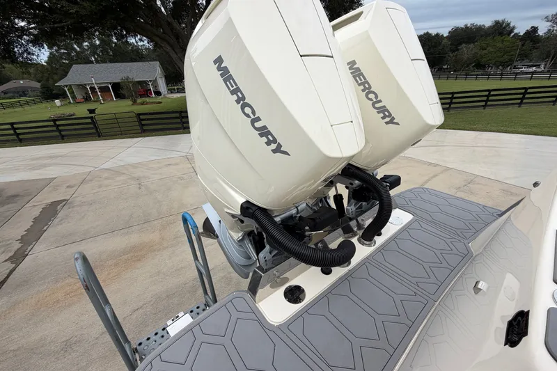 Slide: The Image of 2026 Scout 330 LXF boat with dual Mercury outboard engines on a driveway. - 14
