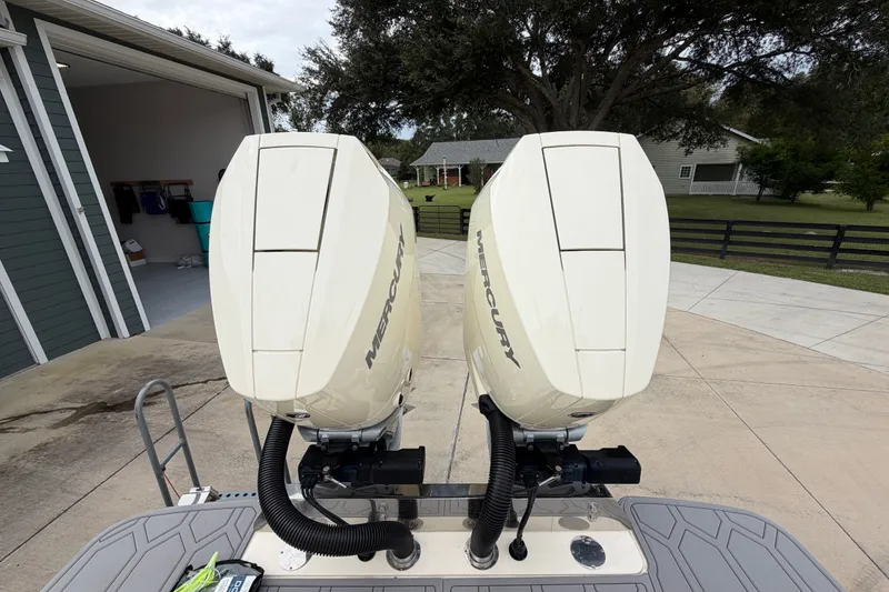 Slide: The Image of Twin Mercury outboard engines on a 2026 Scout 330 LXF boat, parked near a garage. - 13