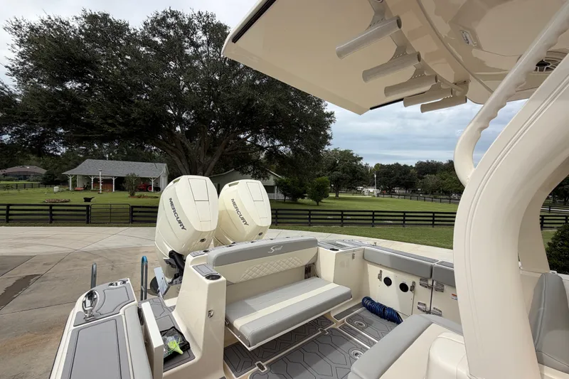 Slide: The Image of 2026 Scout 330 LXF boat with dual Mercury engines, parked near a scenic rural property. - 27