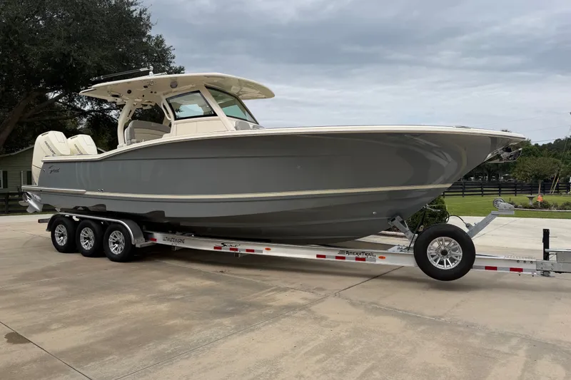 The Image of 2026 Scout 330 LXF boat on trailer, parked outdoors on concrete surface. - 0