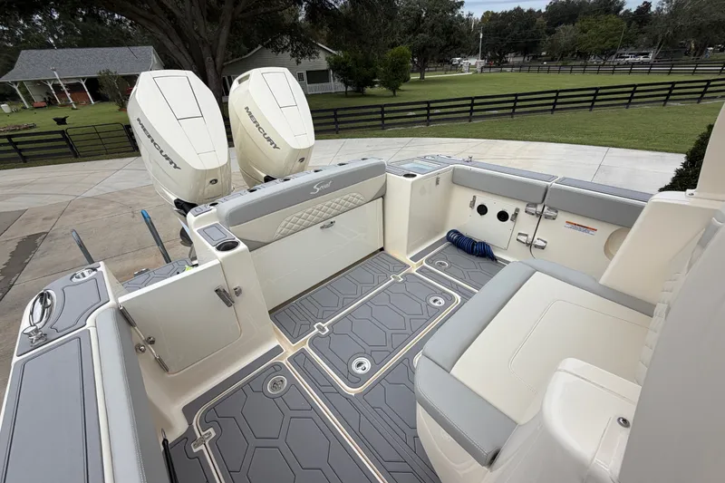 Slide: The Image of 2026 Scout 330 LXF boat interior with dual Mercury engines, gray seating, and deck. - 24