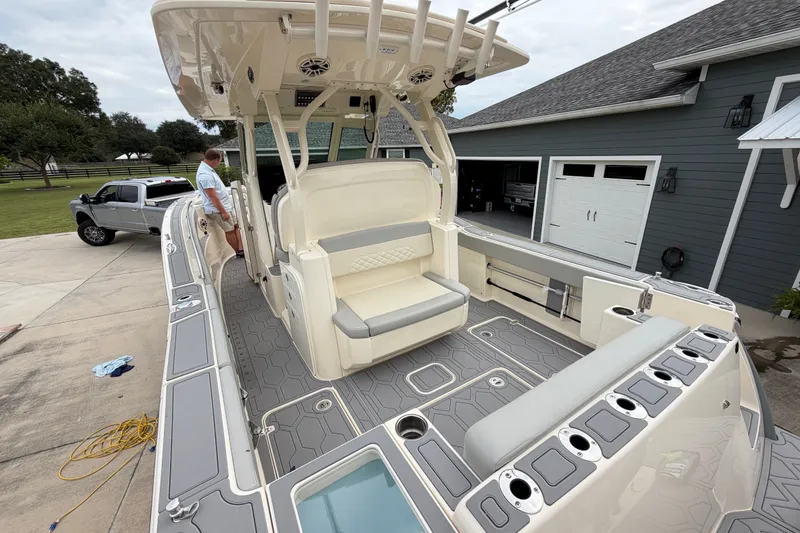 Slide: The Image of 2026 Scout 330 LXF boat with spacious deck and seating, parked near a garage. - 26