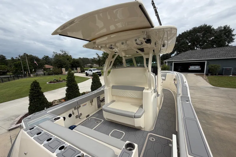 Slide: The Image of 2026 Scout 330 LXF boat with open deck and seating, parked in a driveway. - 28