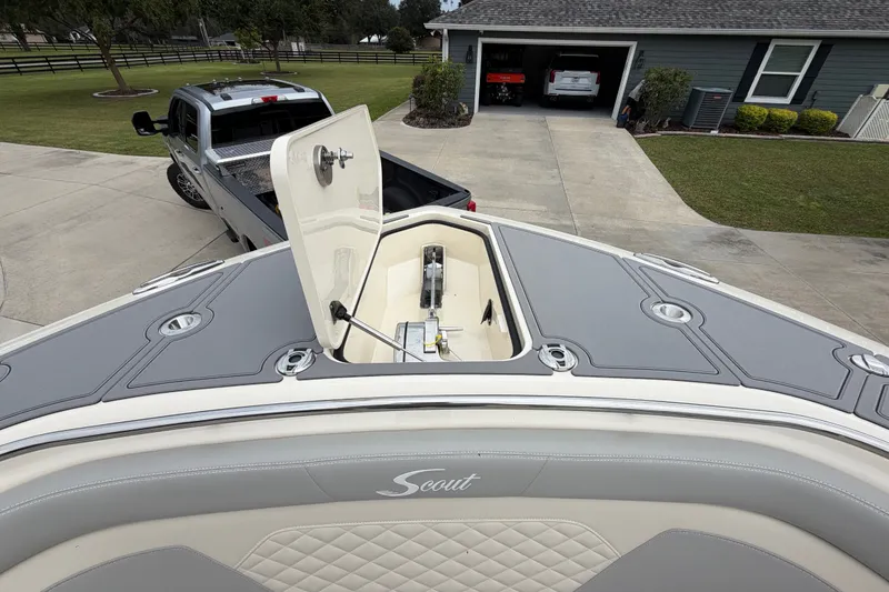 Slide: The Image of 2026 Scout 330 LXF boat on trailer, open hatch, parked in driveway. - 22
