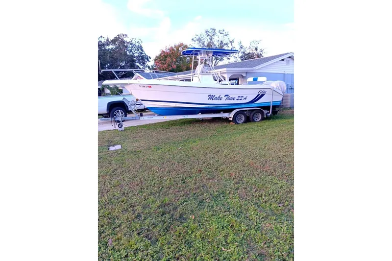 The Image of 2001 Cobia 254 Center Console boat on trailer, parked on grass. - 0