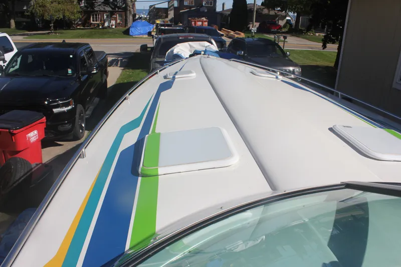 Slide: The Image of 2001 Formula 353 FASTech boat with colorful stripes, parked in a residential driveway. - 7