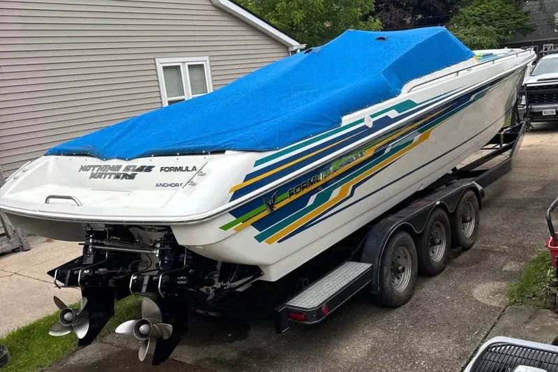 Slide: The Image of 2001 Formula 353 FASTech boat with blue cover on trailer, parked beside house. - 47