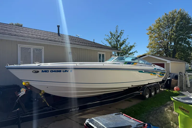 Slide: The Image of 2001 Formula 353 FASTech boat on trailer, parked beside a house under clear blue sky. - 1