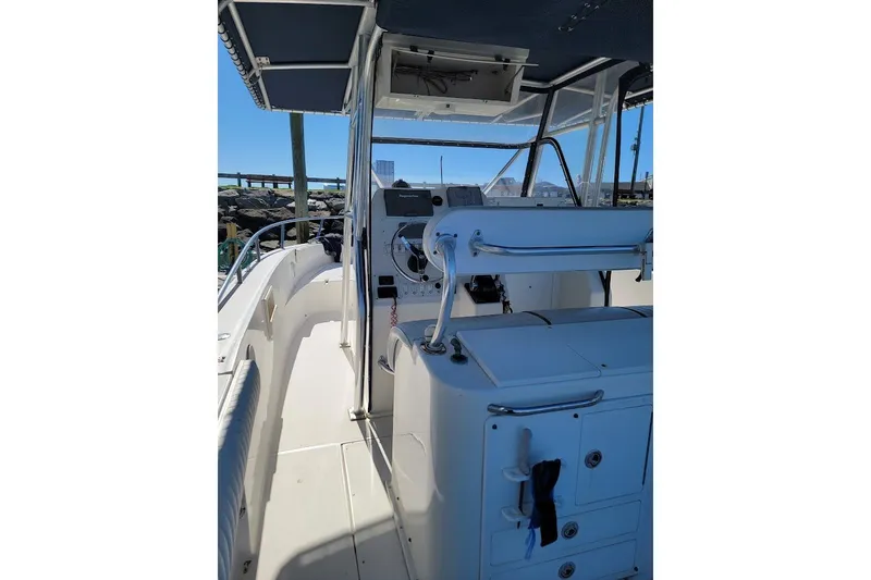 Slide: The Image of 2004 Stamas 310 Tarpon boat interior with helm and seating, docked under clear sky. - 25