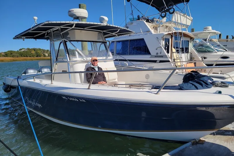 Slide: The Image of 2004 Stamas 310 Tarpon boat docked with a person seated, clear blue sky. - 13
