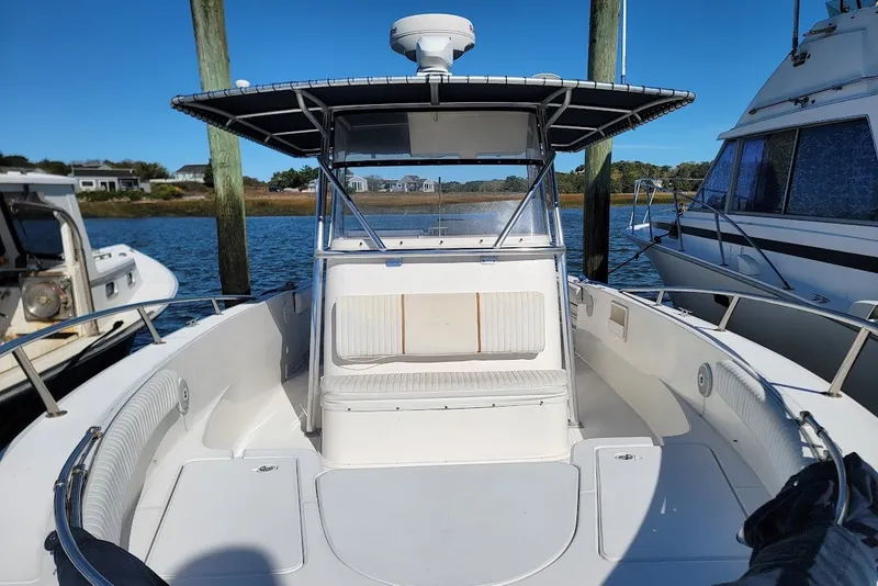 Slide: The Image of 2004 Stamas 310 Tarpon boat docked, featuring spacious seating and a T-top under clear blue skies. - 2