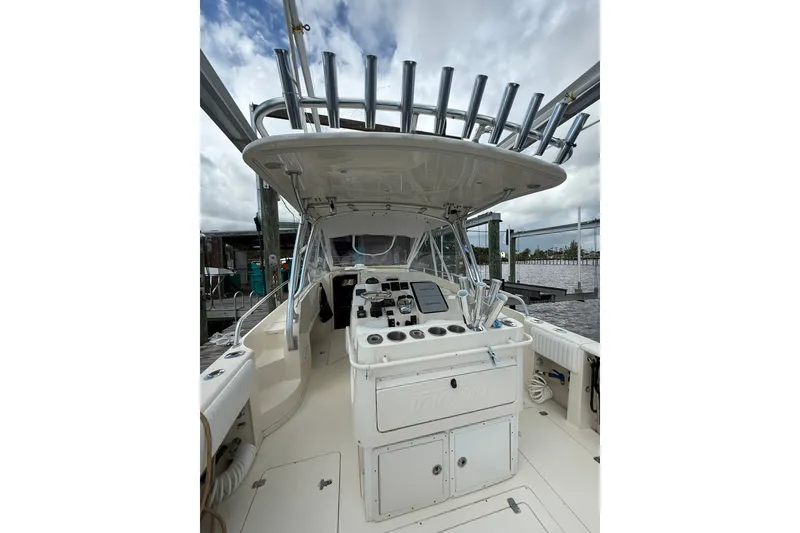 Slide: The Image of 2004 Intrepid 348 Walkaround boat interior with helm, rod holders, and storage compartments. - 26