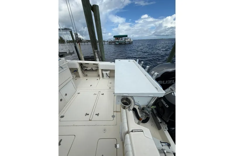 Slide: The Image of 2004 Intrepid 348 Walkaround boat deck with Suzuki outboard motor, docked by the water. - 23