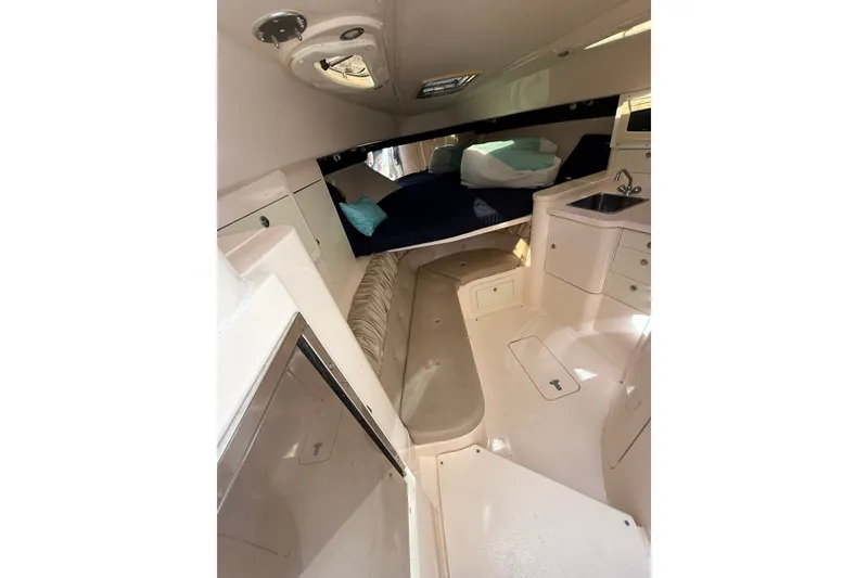 Slide: The Image of Interior of 2004 Intrepid 348 Walkaround boat, featuring cozy cabin and compact kitchenette. - 39