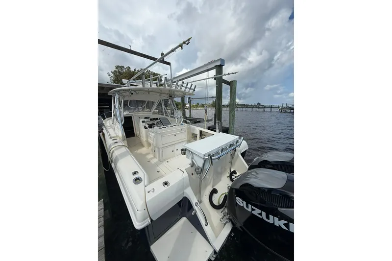 Slide: The Image of 2004 Intrepid 348 Walkaround boat docked, featuring spacious deck and Suzuki outboard engines. - 22
