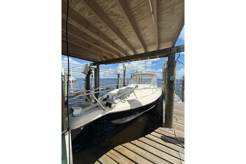 Slide: The Image of 2004 Intrepid 348 Walkaround boat docked under wooden shelter. - 13