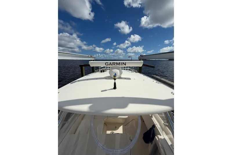 Slide: The Image of 2004 Intrepid 348 Walkaround boat with Garmin radar, docked under a blue sky. - 18