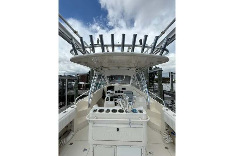 Slide: The Image of 2004 Intrepid 348 Walkaround boat with fishing rod holders, docked under cloudy skies. - 27