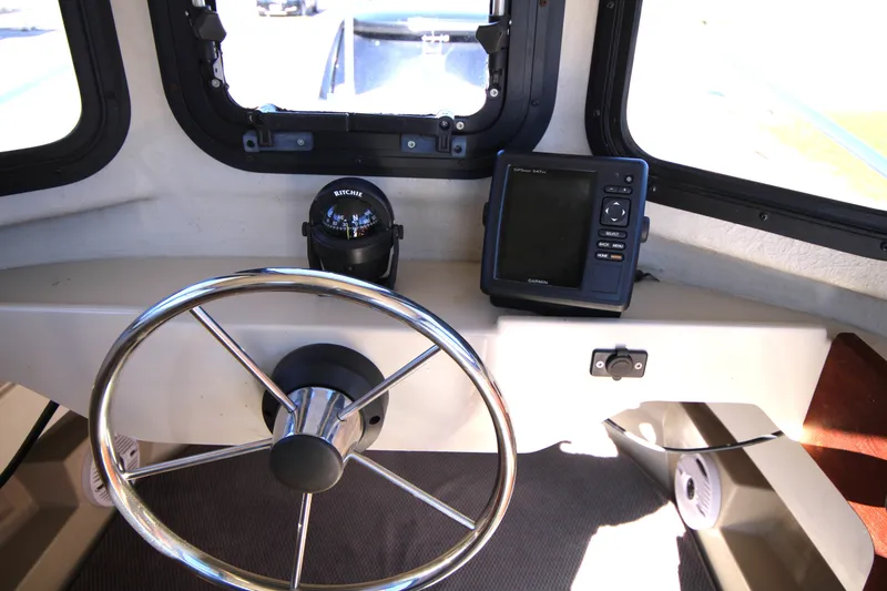 Slide: The Image of 2005 Ranger Tugs R-21 helm with steering wheel, compass, and navigation system. - 21