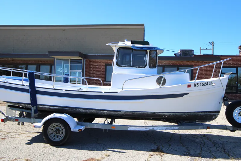Slide: The Image of 2005 Ranger Tugs R-21 boat on trailer, parked in front of a brick building. - 5