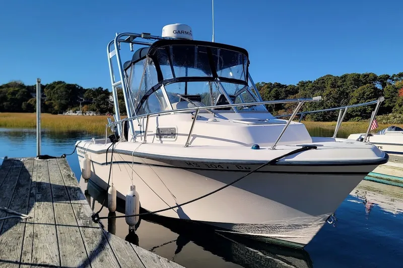 Slide: The Image of 1999 Grady-White Adventure 208 boat docked on calm water under clear blue sky. - 14