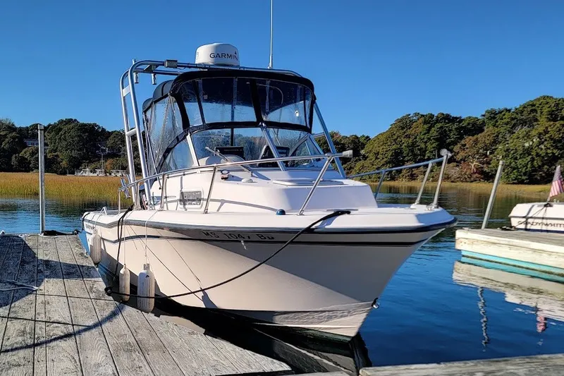 Slide: The Image of 1999 Grady-White Adventure 208 boat docked on a sunny day, surrounded by calm water. - 1