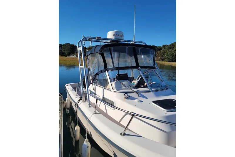 Slide: The Image of 1999 Grady-White Adventure 208 boat docked on calm water under clear blue sky. - 15