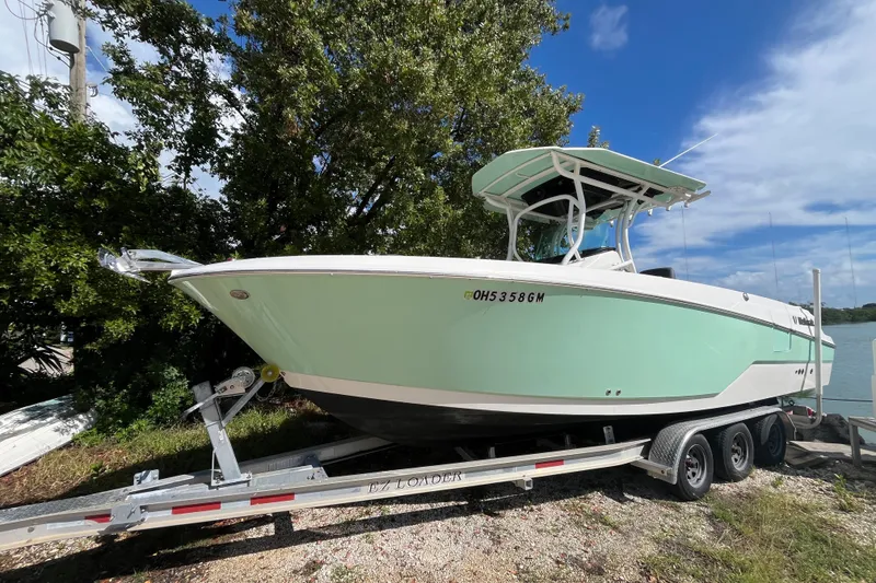 The Image of 2019 Wellcraft 262 Fisherman boat on trailer, parked near trees and water. - 0