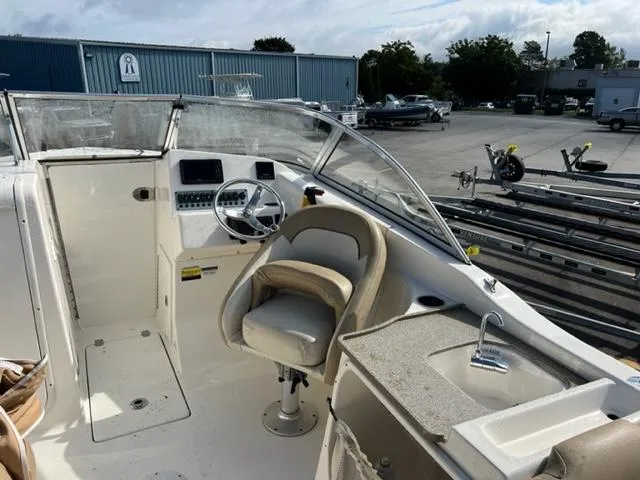 Slide: The Image of 2020 Key West 239 DFS boat interior with helm, seating, and sink in a marina. - 15