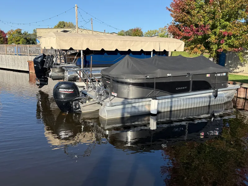 The Image of A 2023 Crest 220 SLC pontoon boat docked, featuring a black cover and Mercury engine. - 0