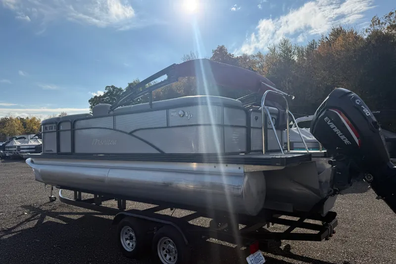 Slide: The Image of 2021 Manitou Aurora 21 pontoon boat on trailer under sunny sky. - 2