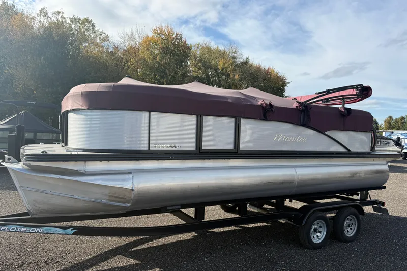 Slide: The Image of 2021 Manitou Aurora 21 pontoon boat with maroon cover on trailer. - 1