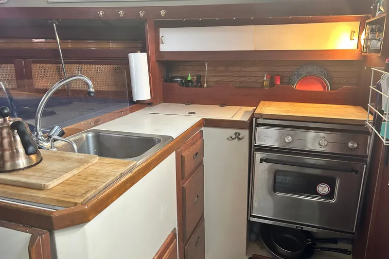 Slide: The Image of 1988 Catalina 34 yacht kitchen with sink, stove, and wooden cabinetry. - 25
