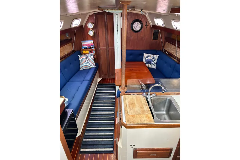 Slide: The Image of Interior of 1988 Catalina 34 sailboat with blue seating, wooden table, and compact kitchen. - 46