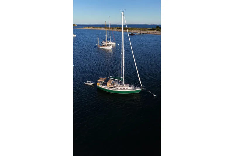 Slide: The Image of 1988 Catalina 34 sailboat anchored in calm waters, with clear blue sky. - 55