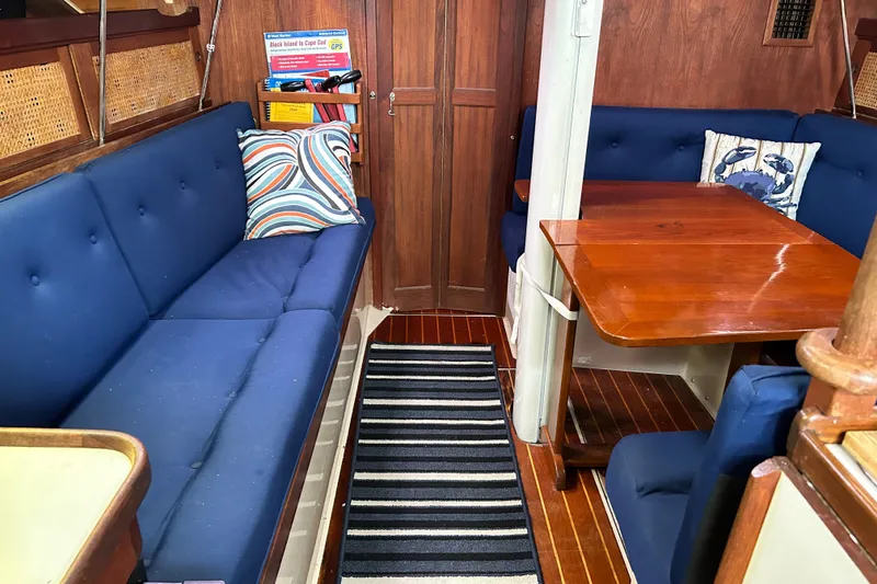 Slide: The Image of Interior of a 1988 Catalina 34 sailboat with blue seating and wooden table. - 16