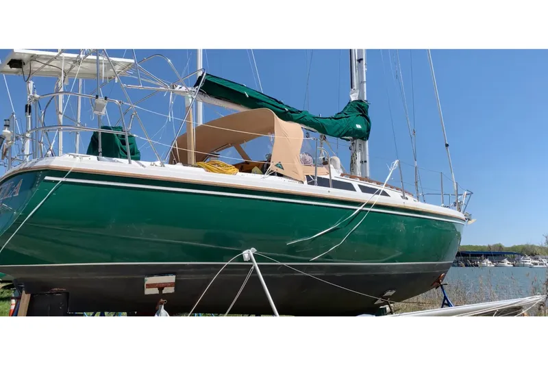 Slide: The Image of 1988 Catalina 34 sailboat with green hull, docked on land under clear blue sky. - 53