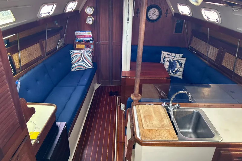 Slide: The Image of Interior of a 1988 Catalina 34 sailboat with blue seating and wooden accents. - 17