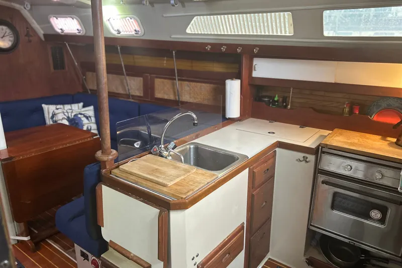 Slide: The Image of Interior of a 1988 Catalina 34 sailboat featuring a compact kitchen and seating area. - 22