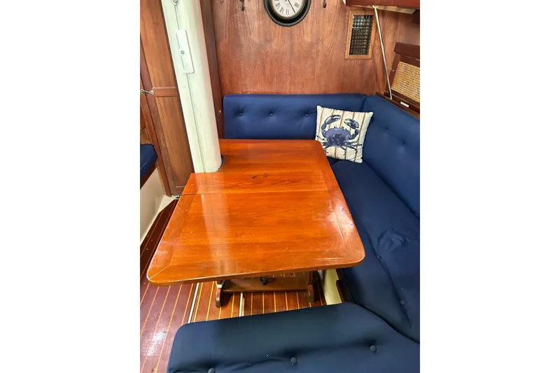 Slide: The Image of Interior of 1988 Catalina 34 sailboat with wooden table and blue cushioned seating. - 15