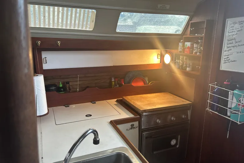 Slide: The Image of 1988 Catalina 34 yacht kitchen interior with stove, sink, and storage shelves. - 43